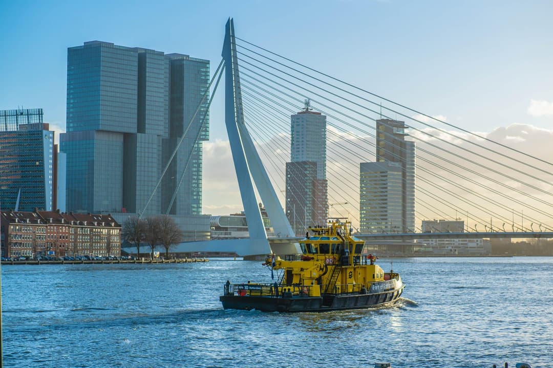 avenvaartuig op de Nieuwe Maas met de Erasmusbrug en de Rotterdamse skyline op de achtergrond